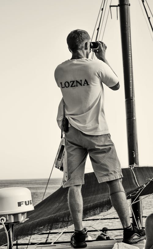 Man Looking through Binoculars on Sailboat