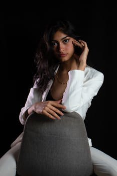 Sophisticated portrait of a woman in white suit on a dark background.