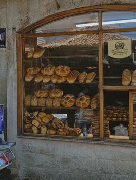 A variety of freshly baked breads on display in a rustic bakery window, inviting and appetizing.