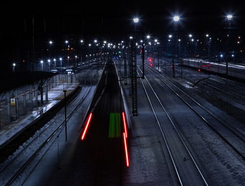 Free Long exposure of a railway station at night capturing dynamic light trails on the tracks. Stock Photo