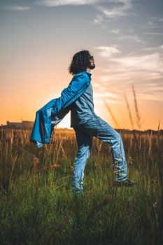 Stylish man in jeans poses outdoors at sunset in Kissimmee, Florida.
