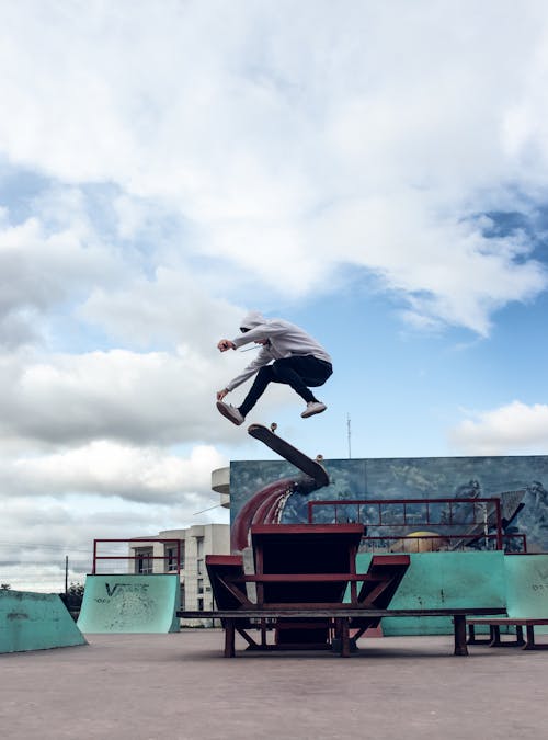 Man Jumping on Skateboard in Skatepark