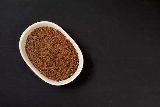 Close-up of ground coffee in a white bowl on a black background for food or beverage concept.