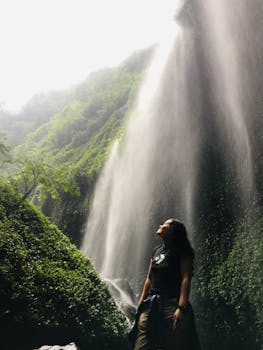 一名女子敬畏地站在绿树成荫的马达卡里普拉瀑布旁，四周一片宁静