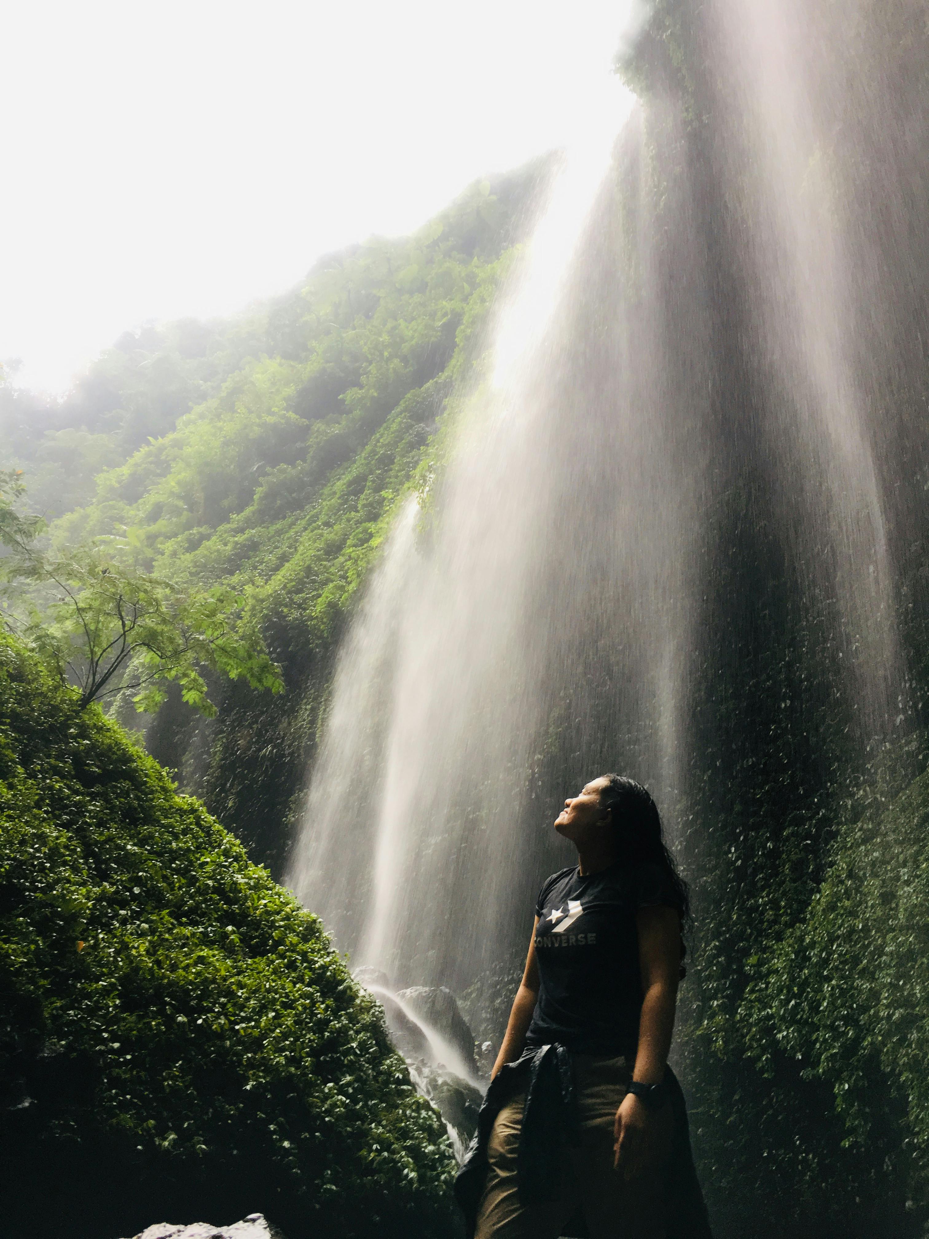 Low Angle Shot Of Woman Standing Under Waterfalls · Free Stock Photo