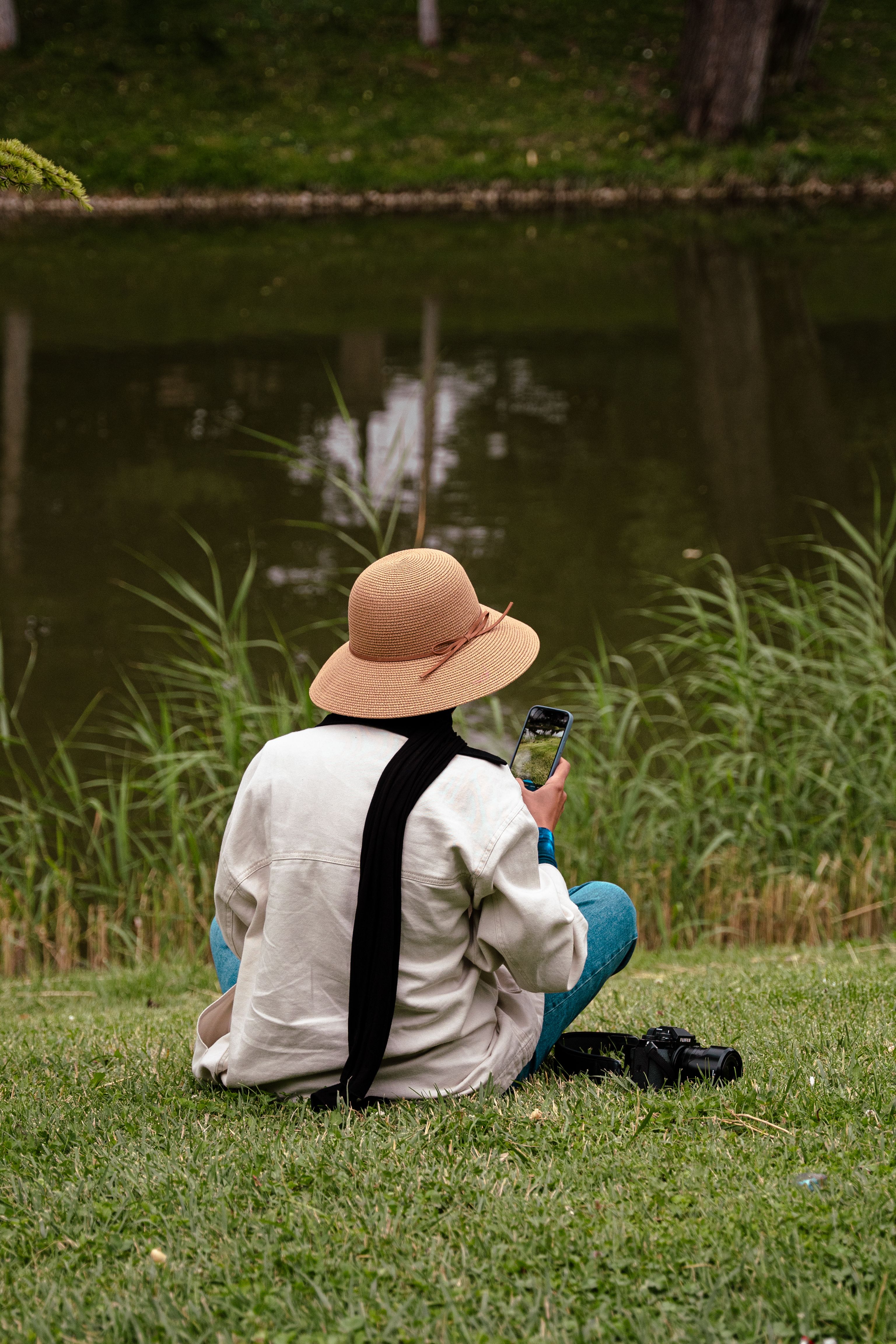 Woman in Hat Sitting on Grass with Cellphone · Free Stock Photo