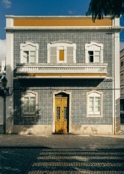 Free Colorful facade of a traditional Portuguese building with decorative tiles and yellow accents. Stock Photo