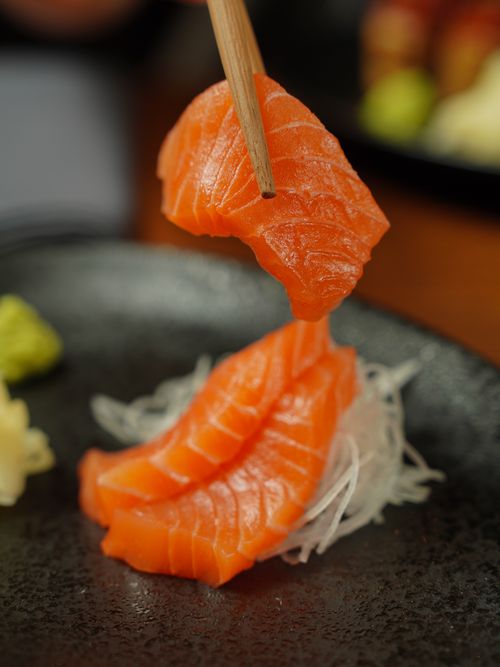 Free Close-up of fresh salmon sashimi being picked with chopsticks, perfect for food photography. Stock Photo