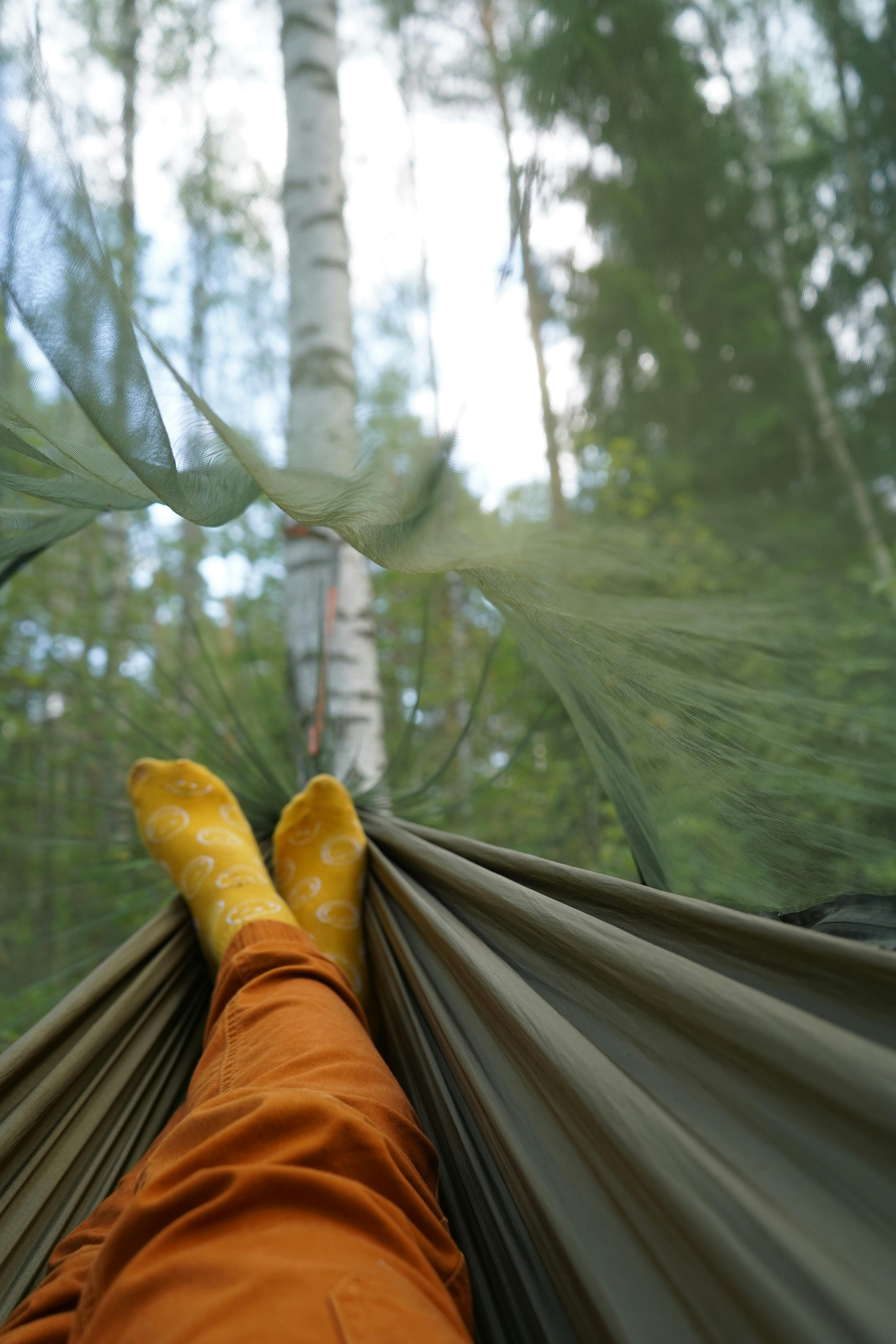 Enjoying leisure time in a hammock under the forest canopy with legs stretched out.