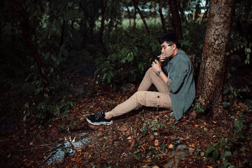 A man sitting in the woods with a cigarette