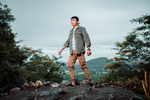 Free A young man confidently hikes on a scenic trail surrounded by lush greenery. Stock Photo