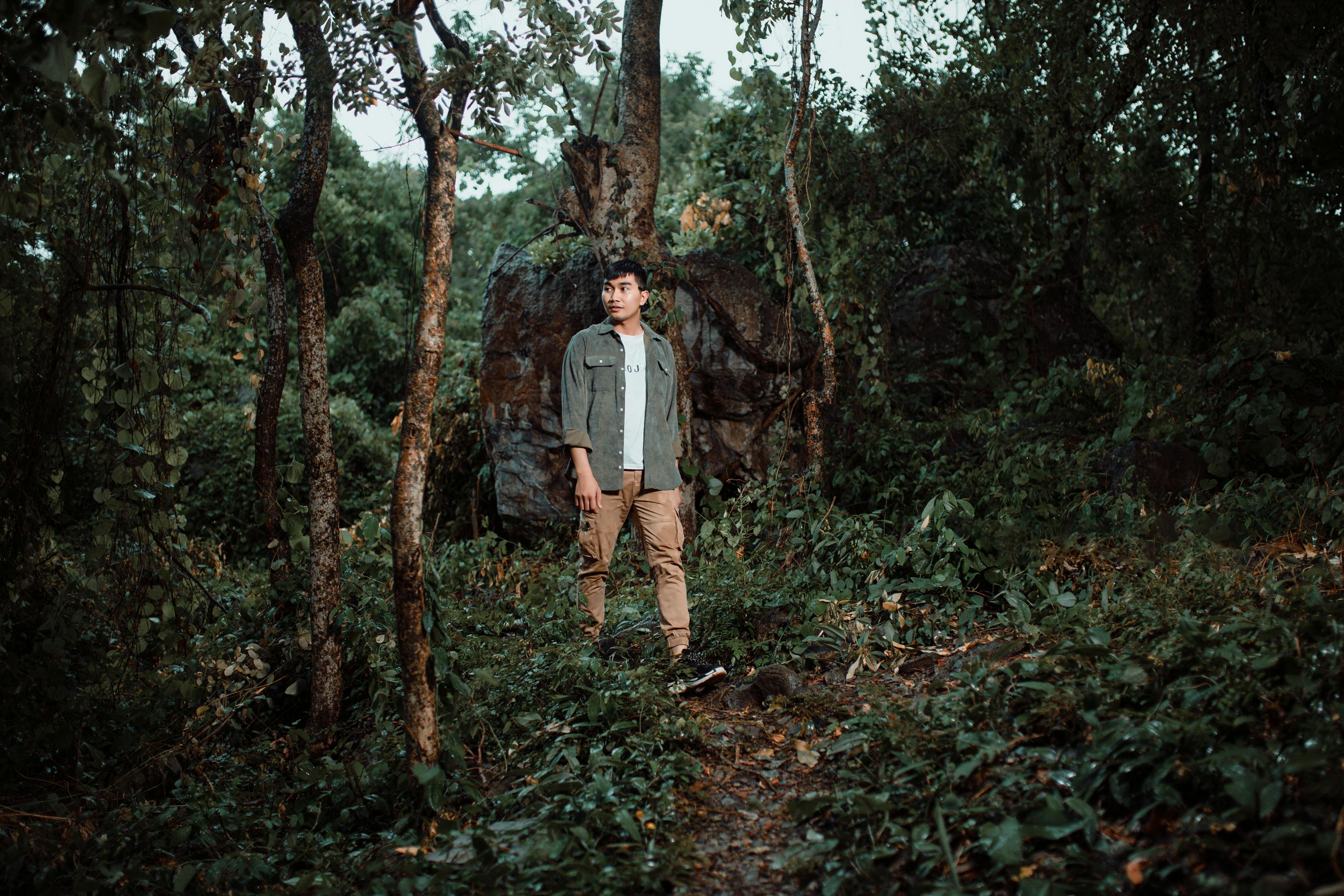 a man standing in the woods with a backpack