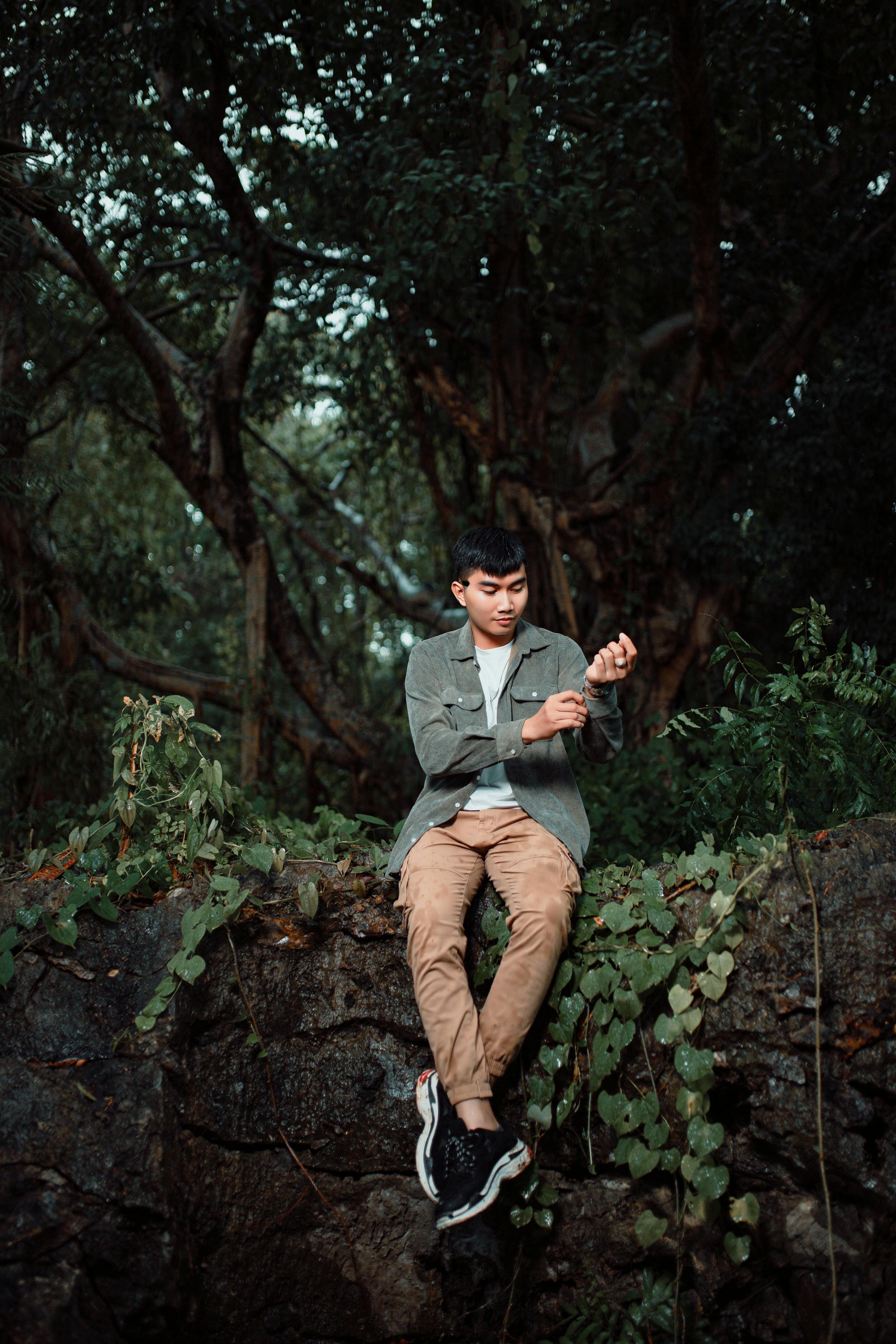 a man sitting on a rock in the woods