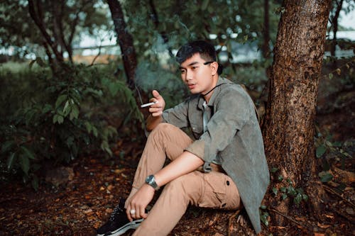 A man sitting in the woods with a cigarette