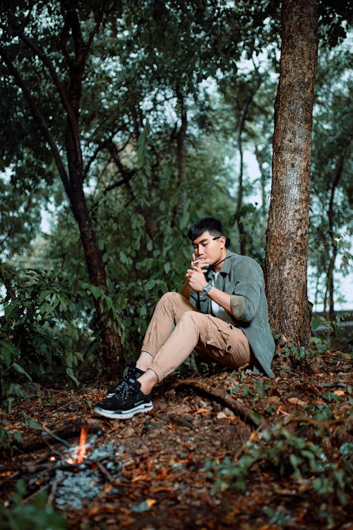 A man sitting in the woods near a campfire