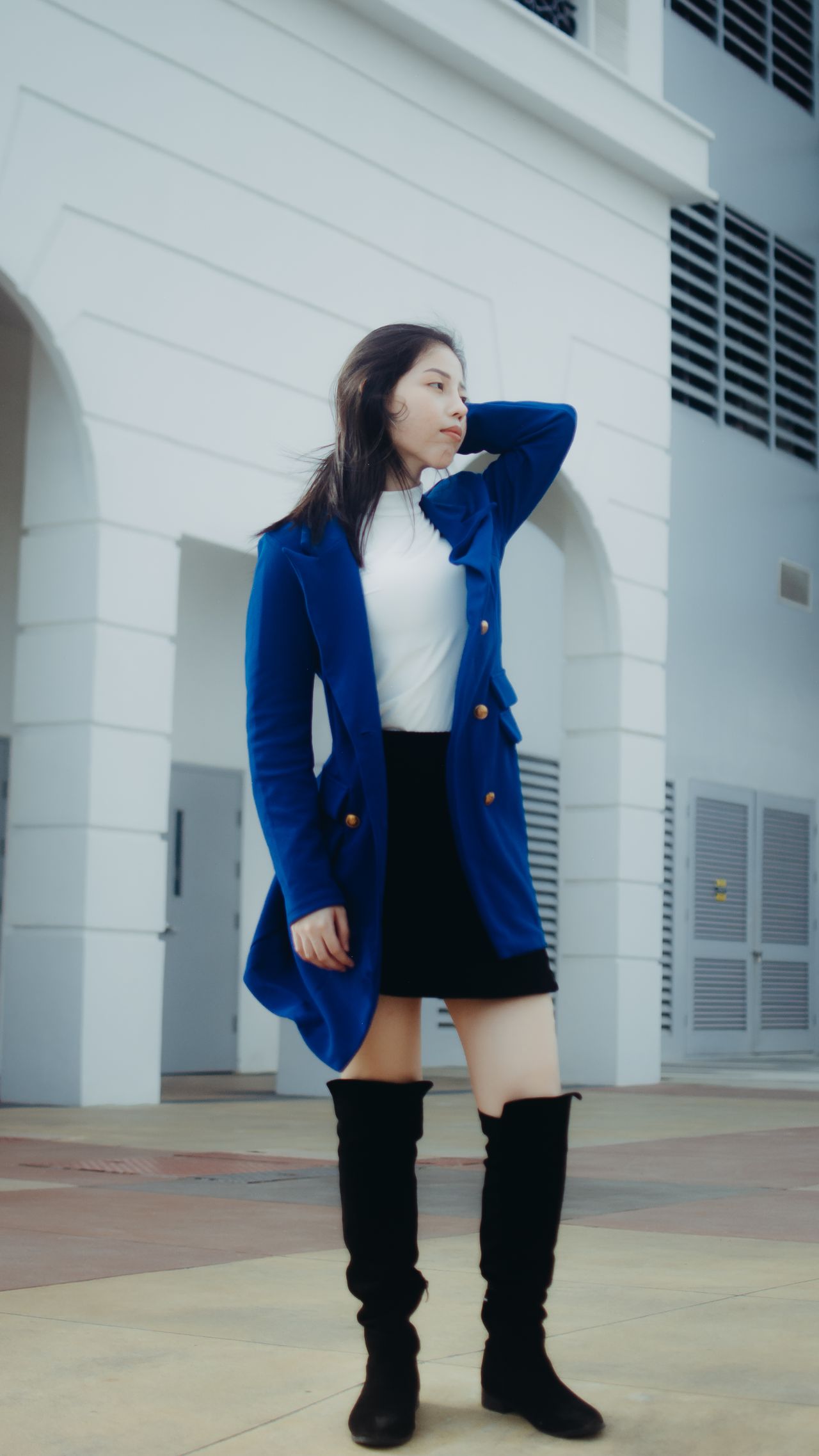 Woman in a blue coat, black mini skirt and black over-knee boots