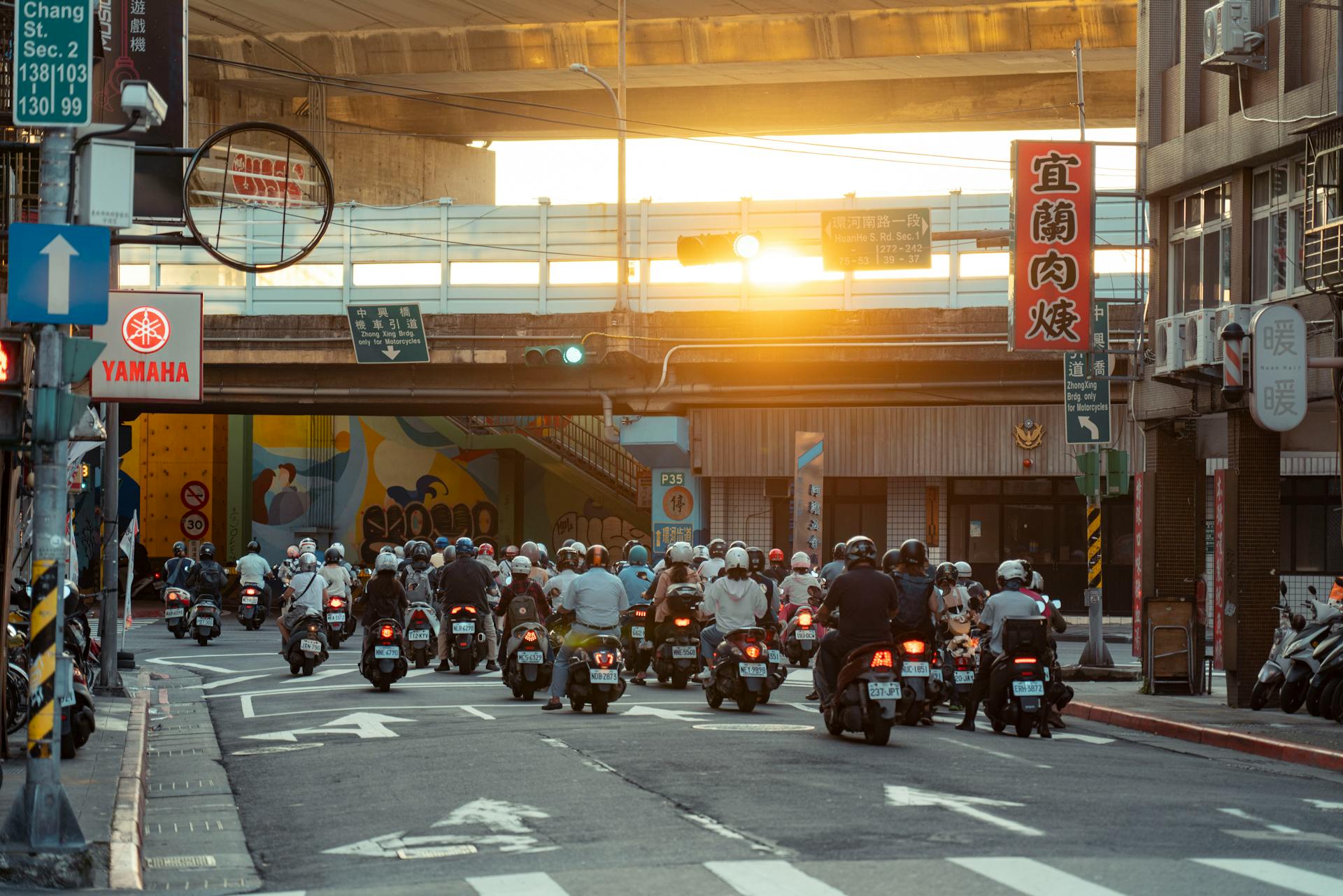 Traffic of scooters at sunset in an Asian city street with urban architecture.