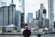 一个人站在布鲁克林，凝视着曼哈顿的天际线全景，那里矗立着摩天大楼