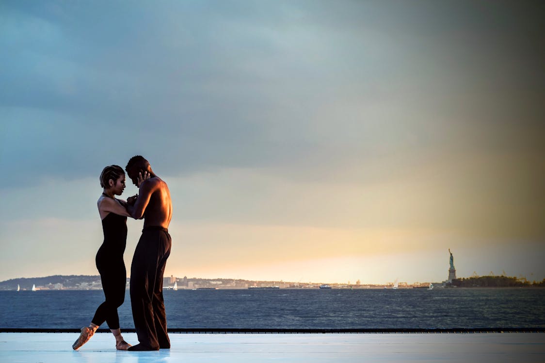 Uomo E Donna Che Balla Vicino Al Corpo D'acqua