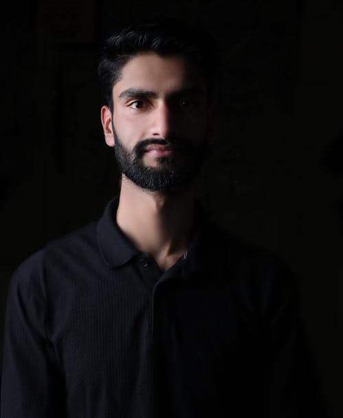 Dark Studio Shot of a Bearded Man in a Black Shirt 