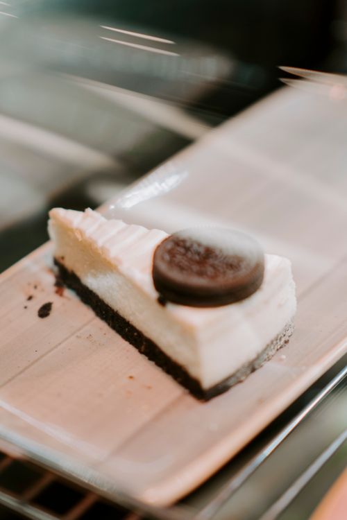 Free A close-up of a creamy cheesecake slice topped with an Oreo cookie on a plate. Stock Photo