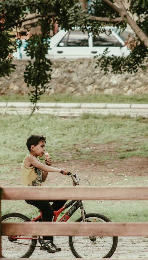 Boy Riding a Bicycle and Eating Ice Creams