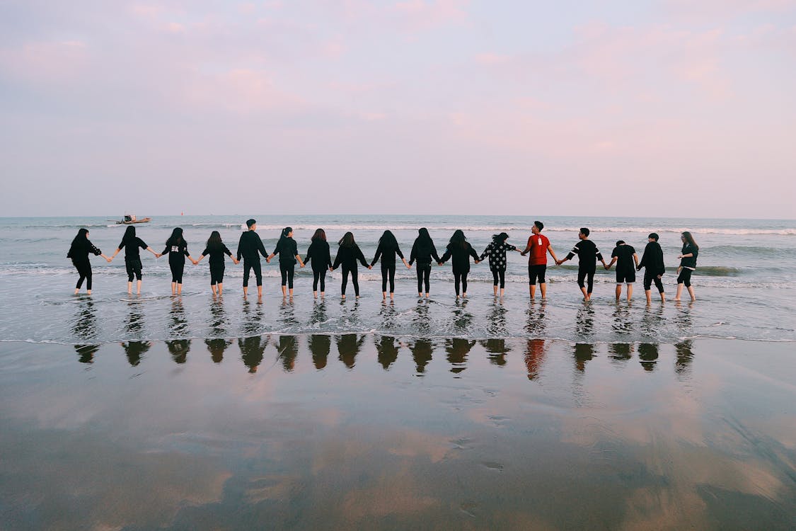 Free Team Holding Their Hands On Seashore Stock Photo