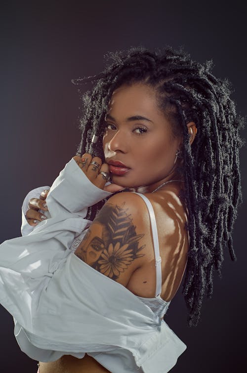 Studio Shot of a Young Woman with an Arm Tattoo, Wearing a White Shirt 