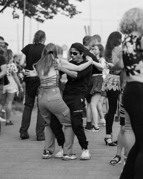 Free A vibrant black and white photo capturing diverse groups dancing joyfully on a city street. Stock Photo