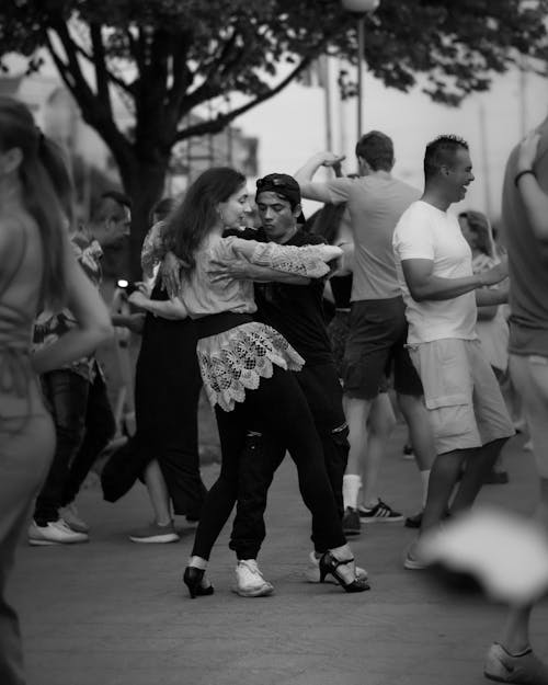 Black and White Photo of People Dancing in Pairs on a Sidewalk in City 