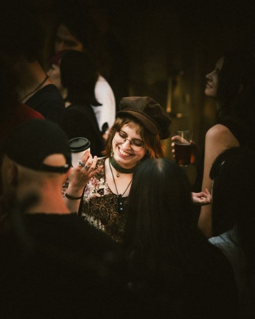 Free Young woman smiling and socializing at a lively nighttime gathering with friends. Stock Photo