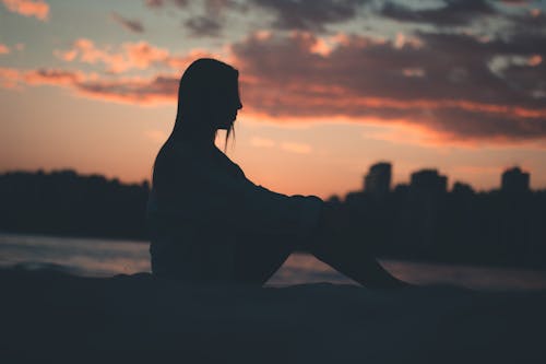 Silhouette of Woman Sitting on Rock