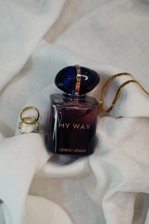 Free Luxury perfume bottle and gold jewelry on soft white fabric create an elegant scene. Stock Photo