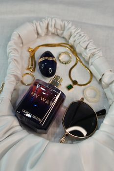 Stylish flat lay of perfume and accessories on fabric, showcasing elegance.