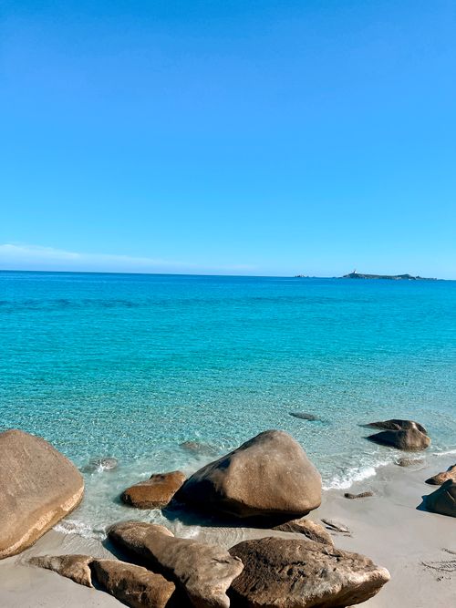 Free Peaceful beach scene with azure sea and rocks on a sunny day. Stock Photo