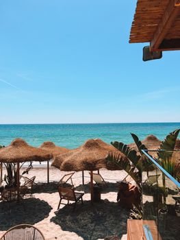 Scenic view of a tropical beach resort featuring straw umbrellas and wooden chairs, perfect for vacations.