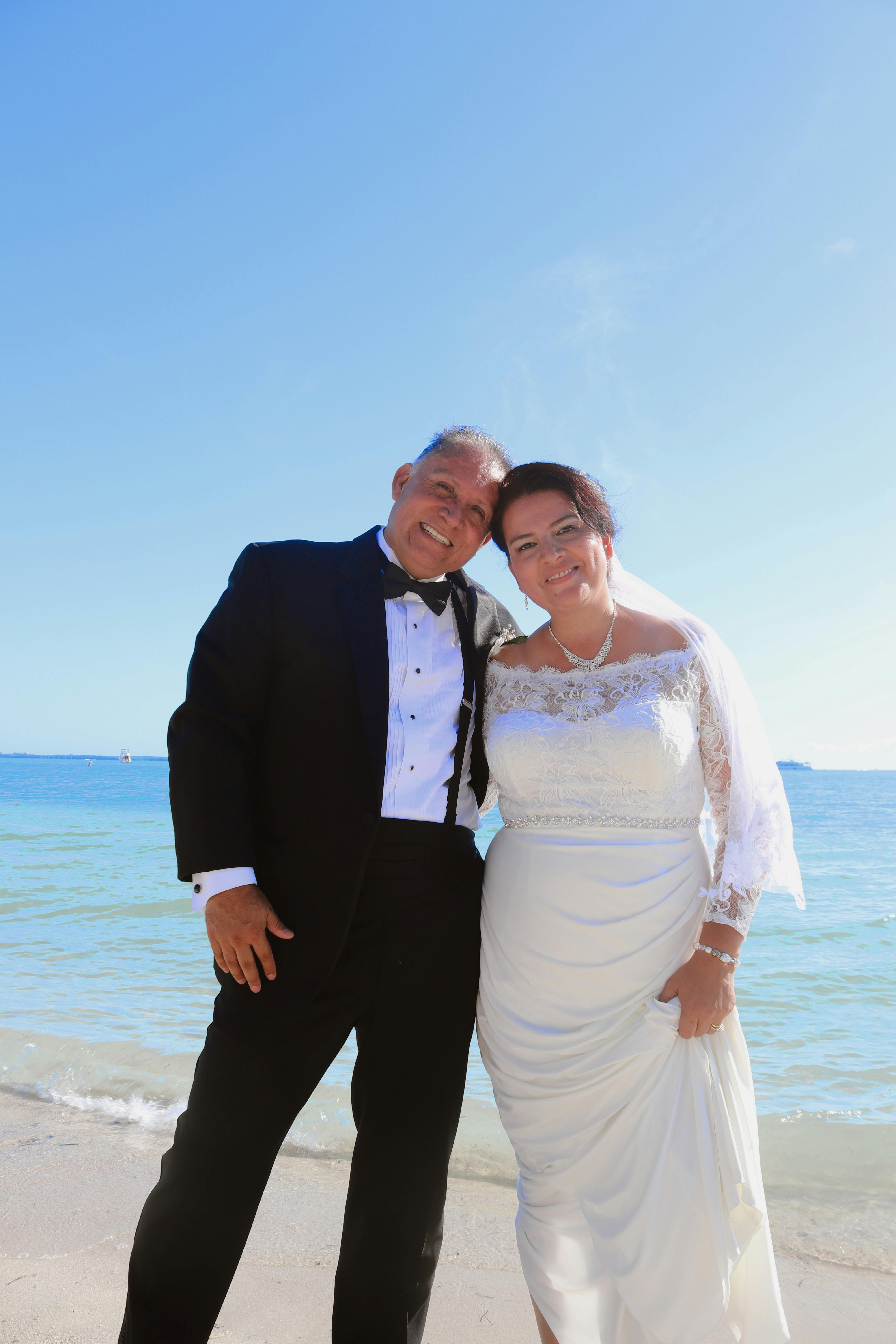 A joyful couple in wedding attire on a sunny Miami beach.