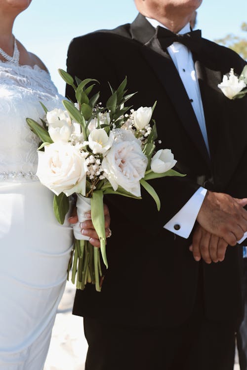 Photo of Bride and Groom Standing Outside in Sunlight 