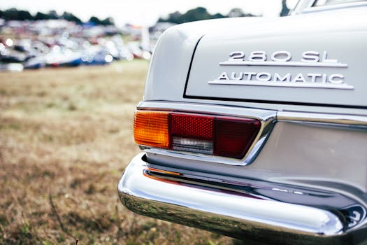 Close-up of a vintage Mercedes 280 SL showcasing its tail light and chrome details at an outdoor car show.