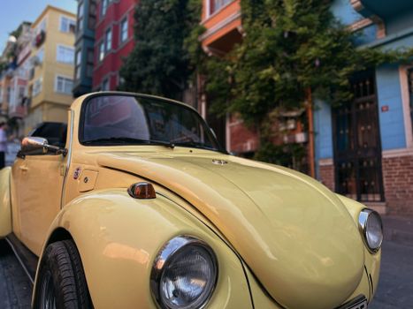 A classic yellow Volkswagen Beetle parked on a vibrant, colorful street.