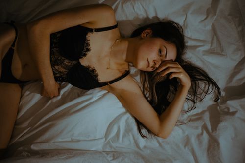 Free A woman in lingerie lying on a bed, captured in a serene and relaxed pose indoors. Stock Photo