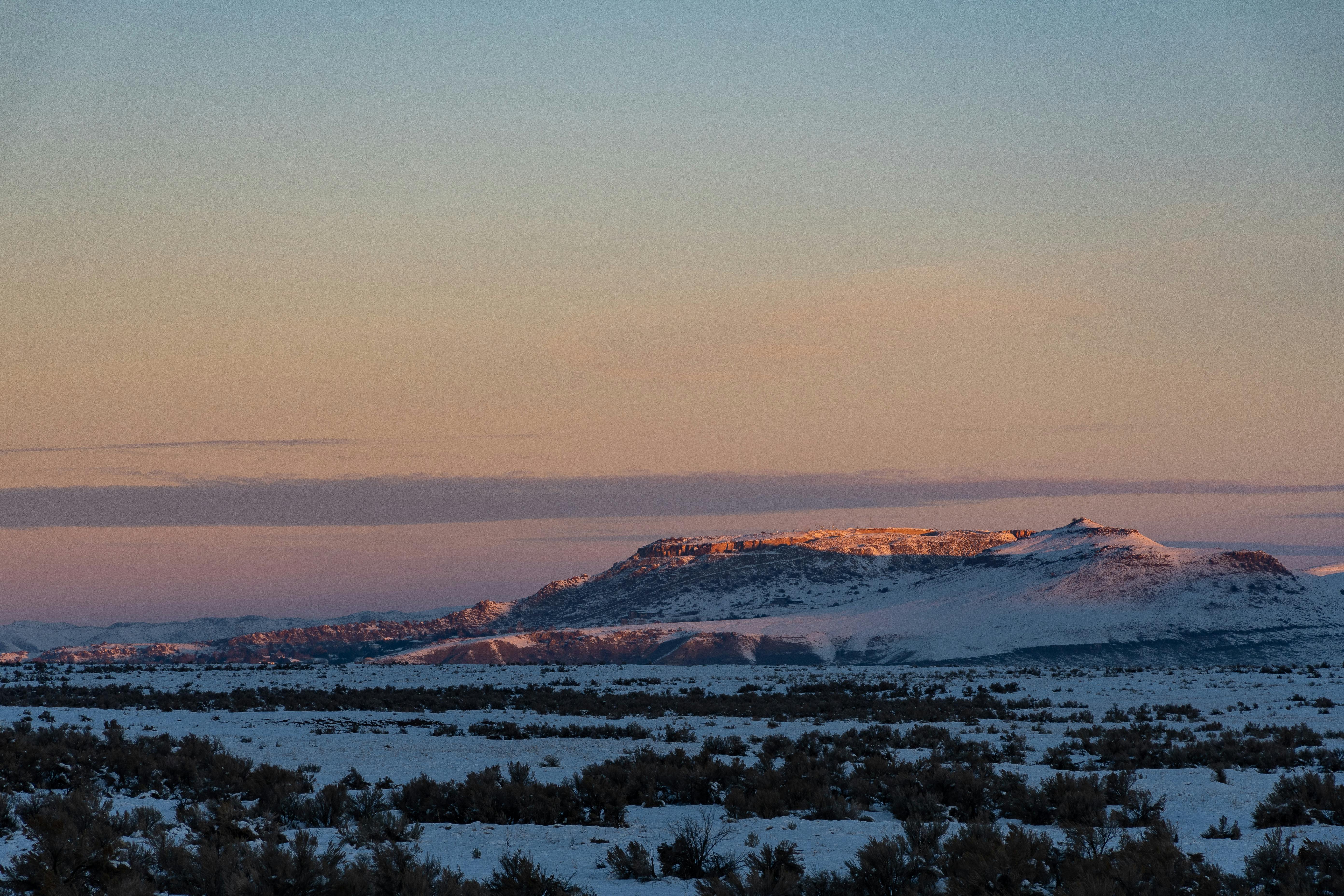 日落时分，白雪覆盖的山峰风景优美，展现出大自然的宁静之美