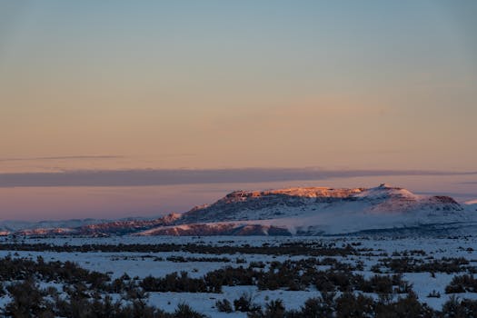 日落时分，白雪覆盖的山峰风景优美，展现出大自然的宁静之美