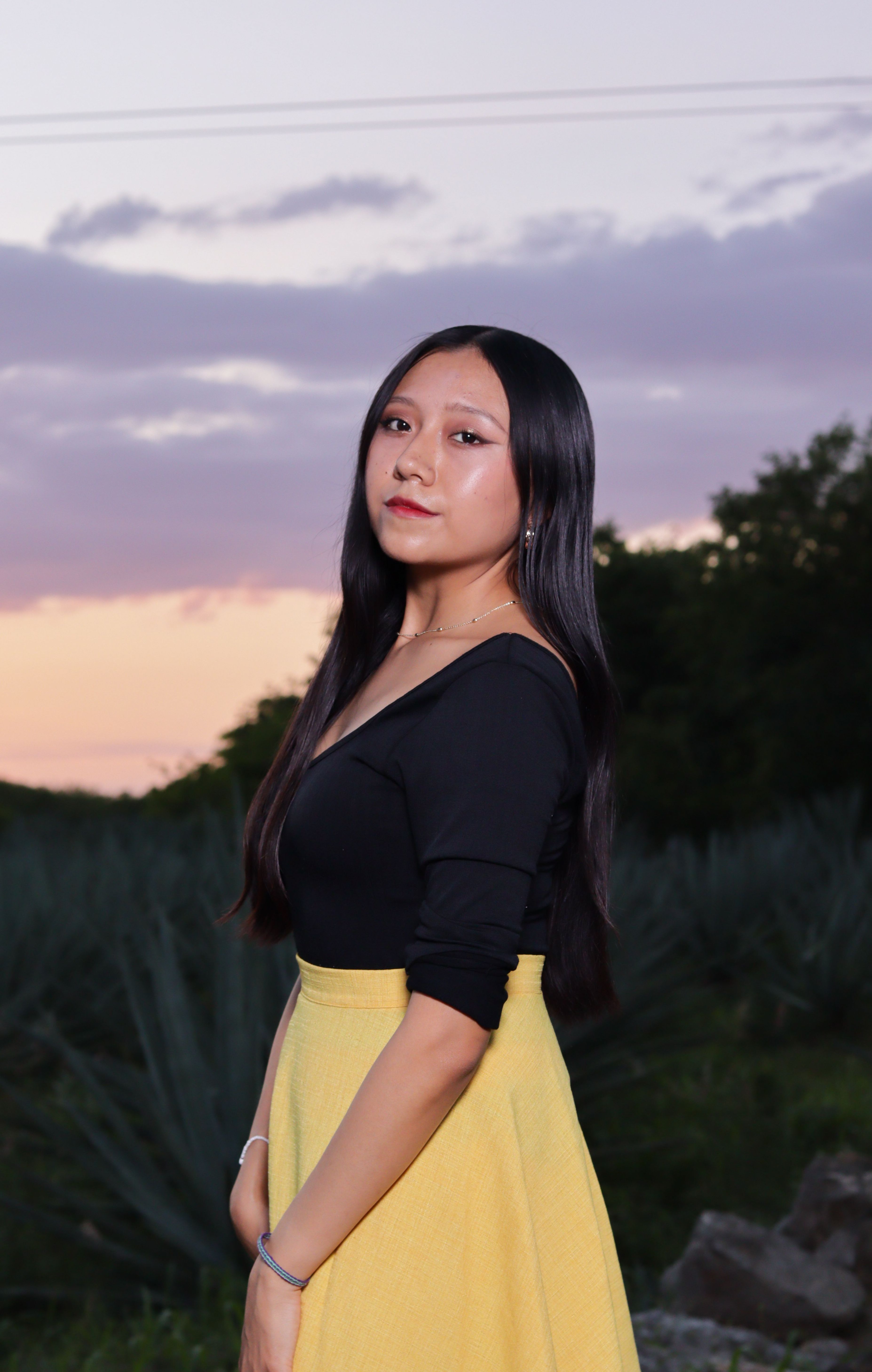 Portrait of a woman in a yellow skirt outdoors at sunset, showcasing fashion and elegance.