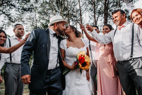 Newlywed Couple Kissing with Guests Raising a Toast 