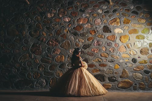 新娘holidng花与背对着镜头站在一堵石墙前的照片