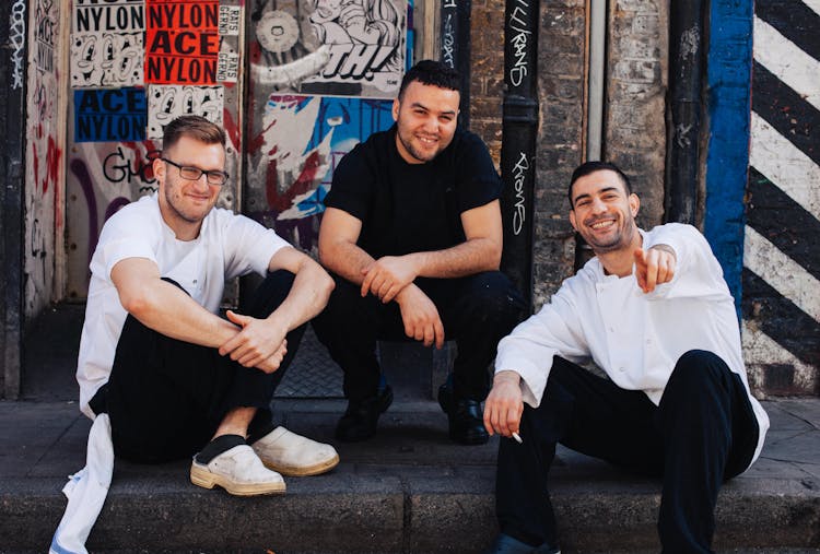 Three Men Sitting On Street Curb