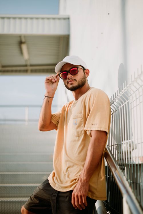 Free Stylish man adjusts sunglasses in urban environment, exuding cool vibes. Stock Photo