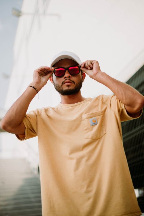 Free Stylish man in sunglasses and cap posing in an urban setting, wearing casual attire. Stock Photo