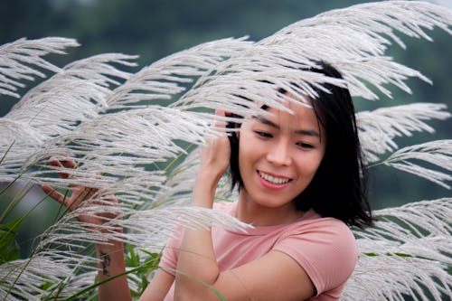 Young Woman Standing between High Ornamental Grass 